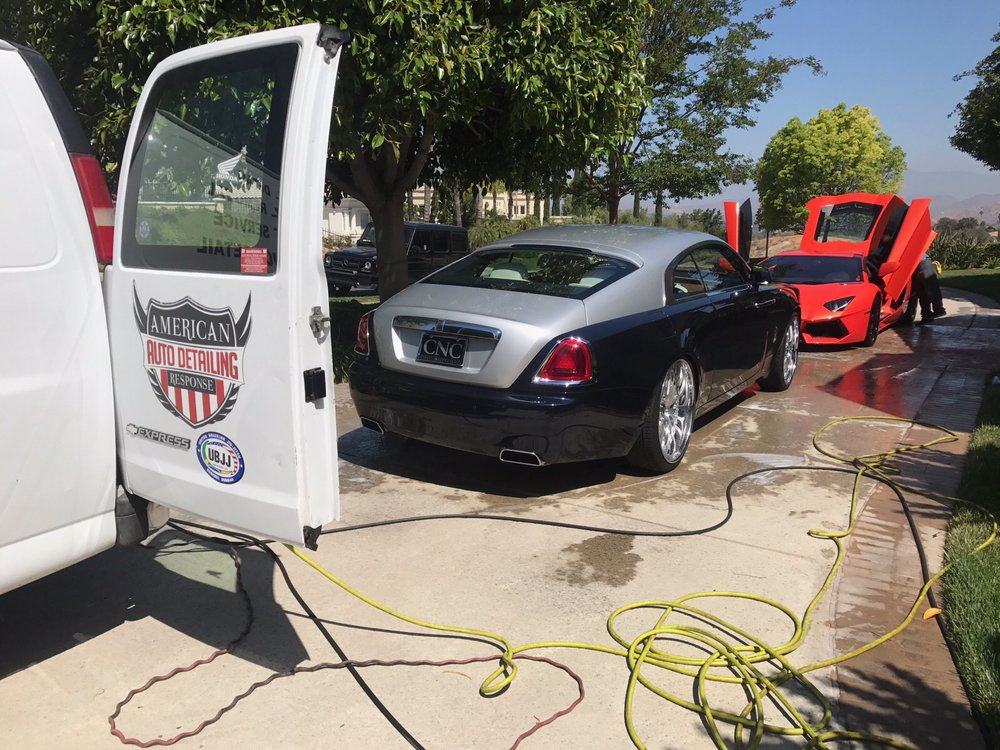 On-site car detailing in progress with American Auto Detailing van and luxury cars.