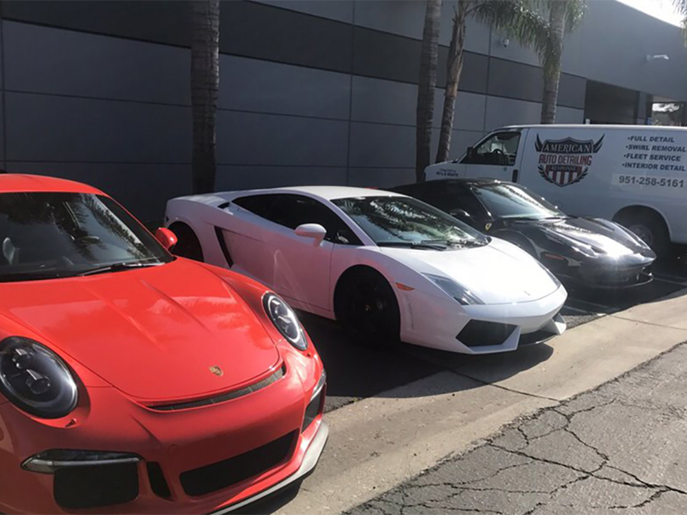 Technician polishing car exterior during professional detailing service.